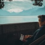 Vecchio sul lago con libro